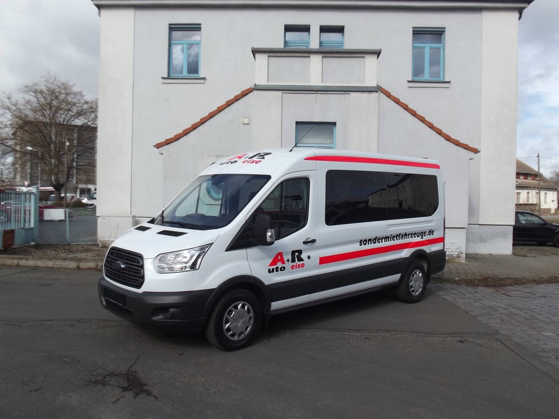 Ford Transit in Weiß mit A+R-Beschriftung vor einem Gebäude